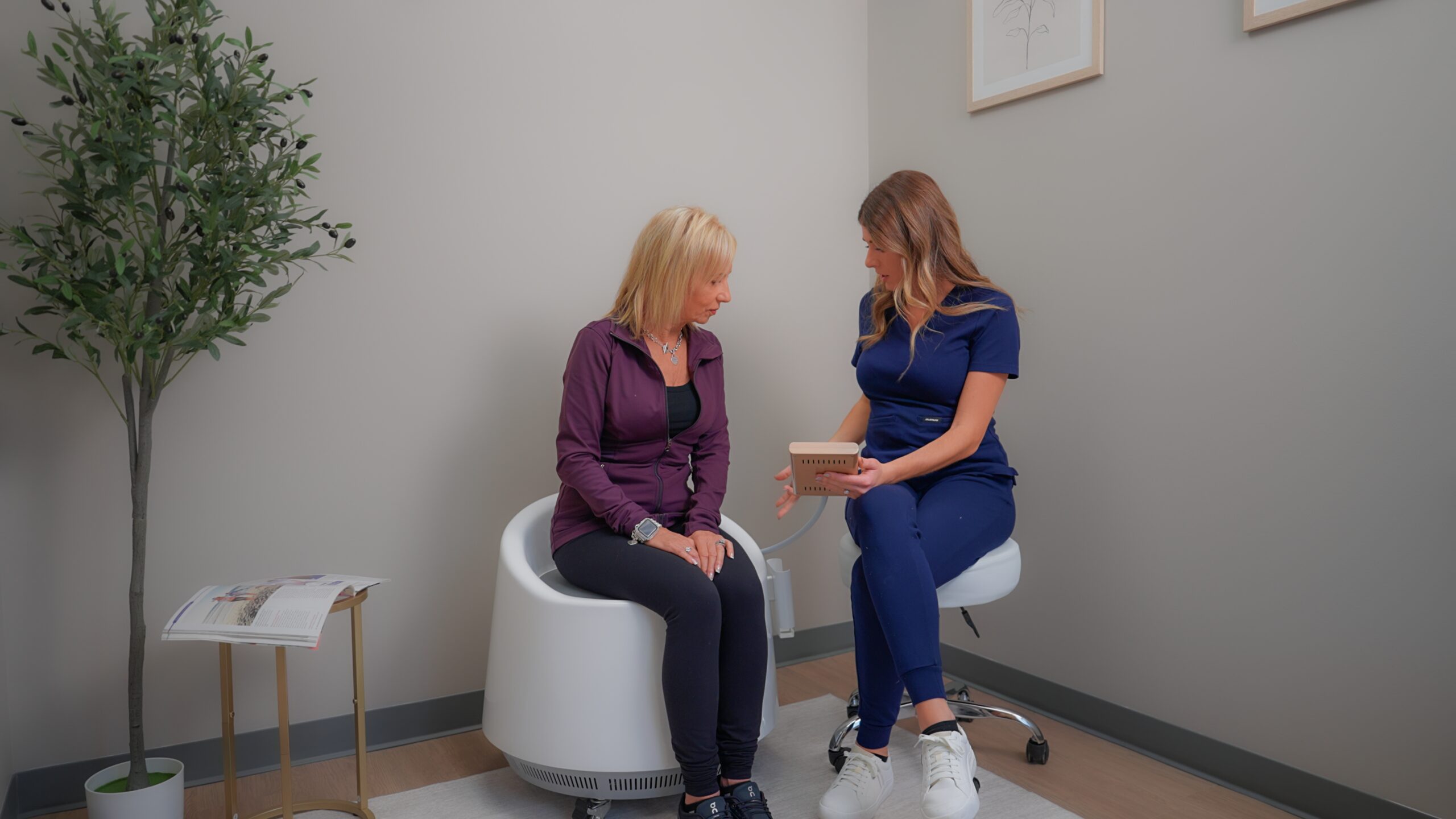 Dr. Meghan Bissell from The Renew Studio in Downtown Romeo explaining while a woman is sitting on the Restora EMS Chair