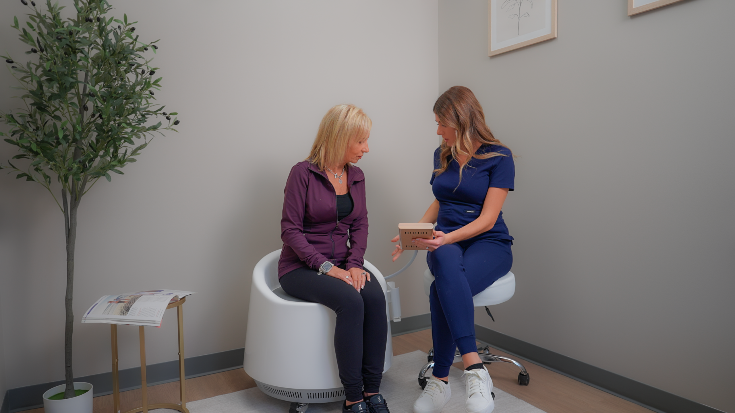 Dr. Meghan Bissell from The Renew Studio in Downtown Romeo explaining while a woman is sitting on the Restora EMS Chair